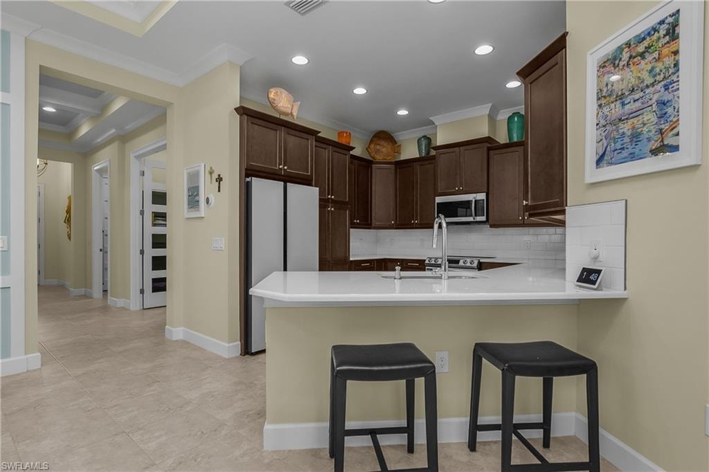 Kitchen featuring dark wood cabinetry, white countertops, stainless steel appliances, and a white subway tile backsplash