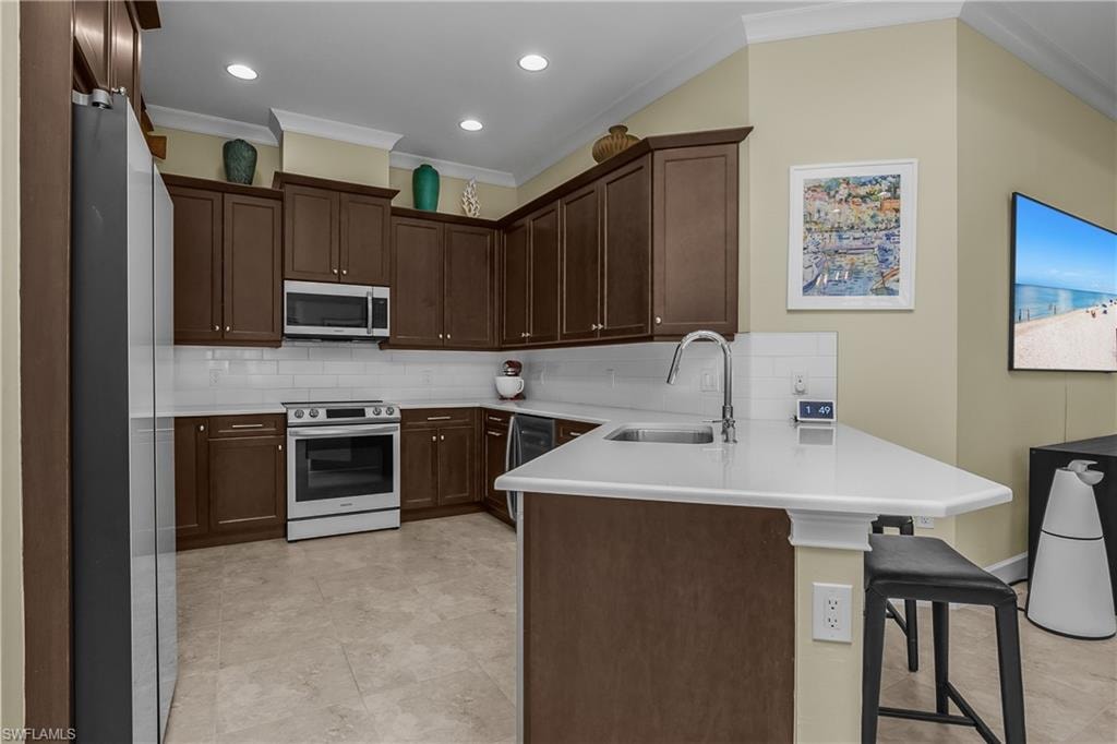 Kitchen featuring dark wood cabinetry, stainless steel appliances, white subway tile backsplash, light-toned countertops, and recessed lighting