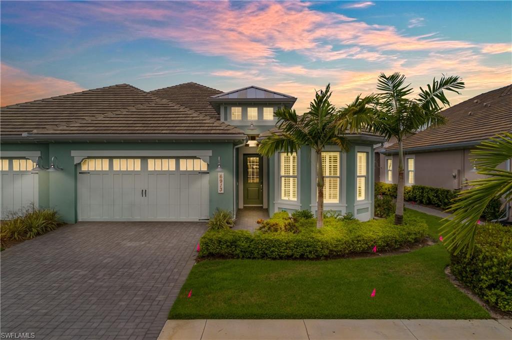 Exterior featuring a tiled roof, stucco siding, paver driveway, bay window, and manicured landscaping