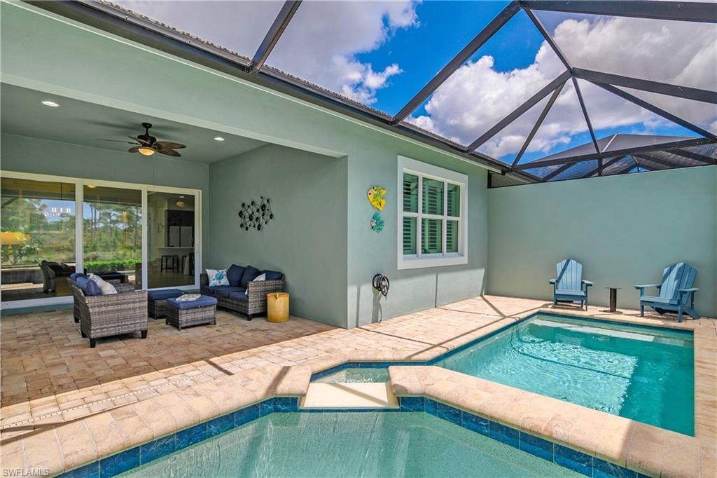 Screened-in outdoor living space with a swimming pool featuring a spa, a covered patio with a ceiling fan, and sliding glass doors