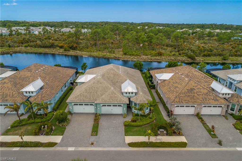 Waterfront property featuring a tile roof, paver driveway, and mature landscaping