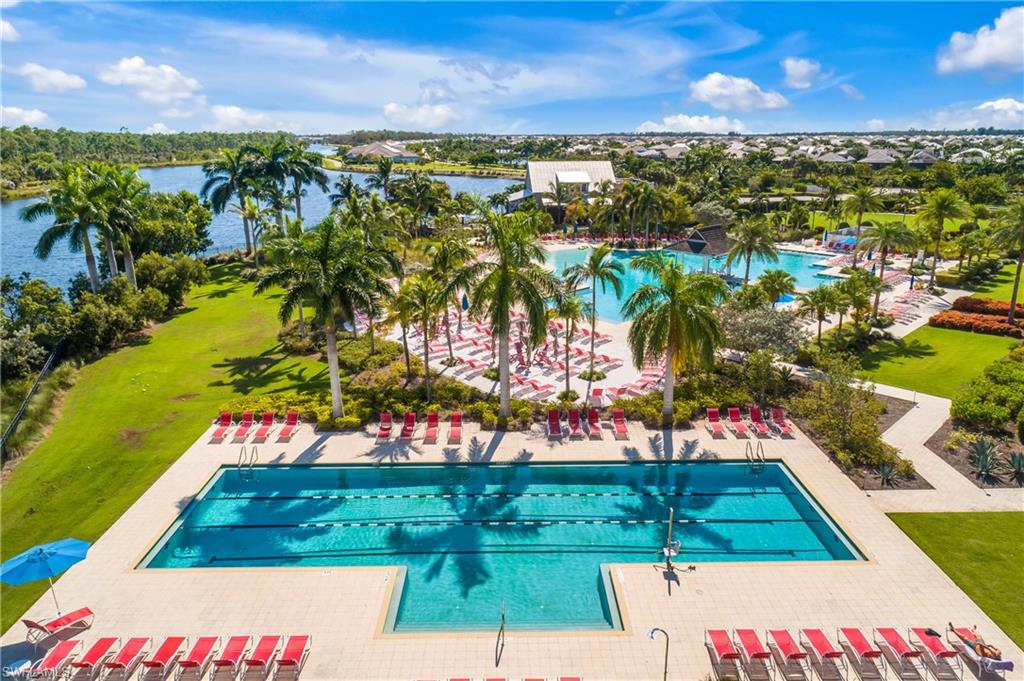 Expansive aquatic area featuring a multi-lane lap pool, a large resort-style pool with a gradual entry, and multiple sun deck areas with lounge seating
