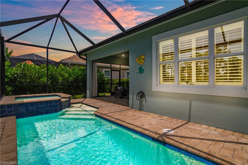 Screened enclosure with a swimming with integrated spa, and paver decking