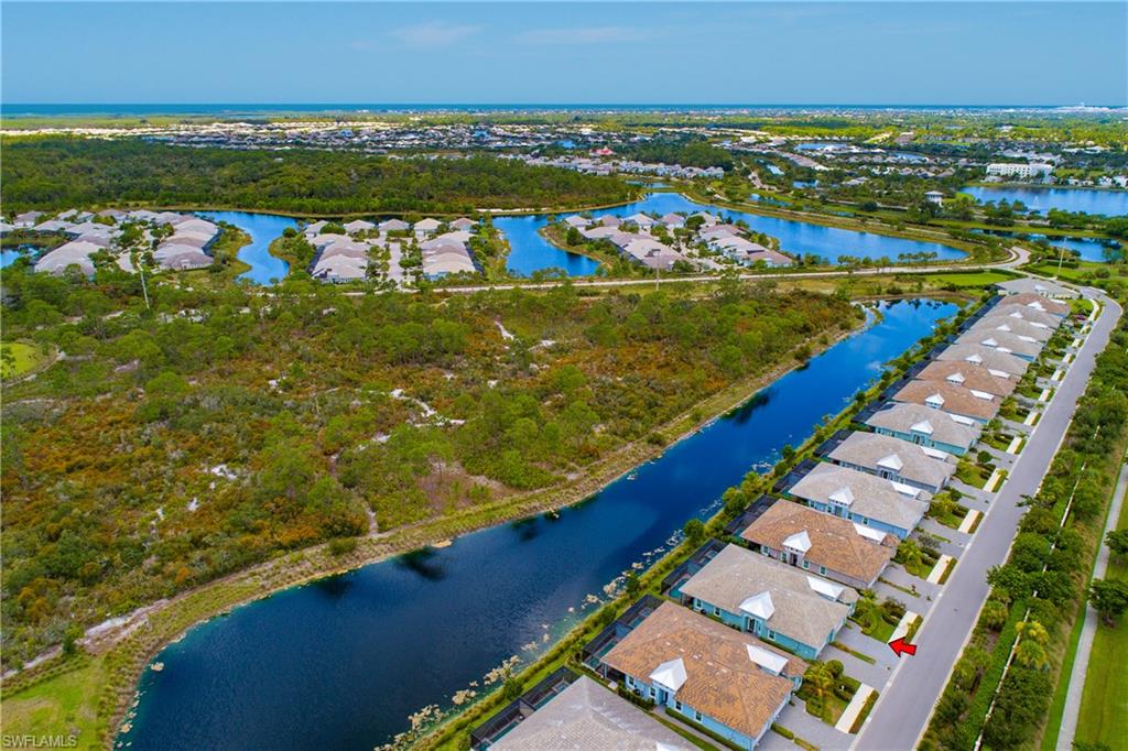 Coastal community with multiple homes, a water feature, and paved roadways, set against a natural landscape