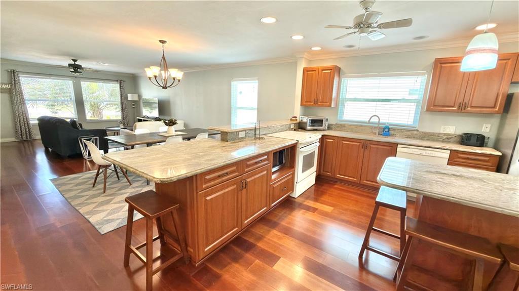 Expansive wood-finish flooring throughout, kitchen featuring wood cabinetry, stone countertops.