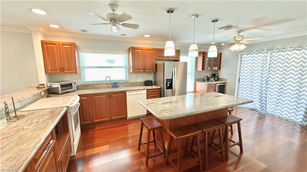 Kitchen featuring wood-finish flooring, recessed lighting, a kitchen island with pendant lighting, wood cabinetry.