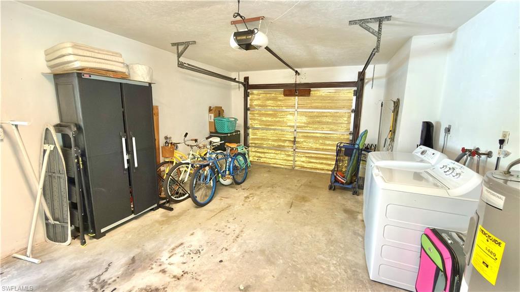 Concrete flooring garage space with overhead lighting, a garage door opener system, and white painted walls