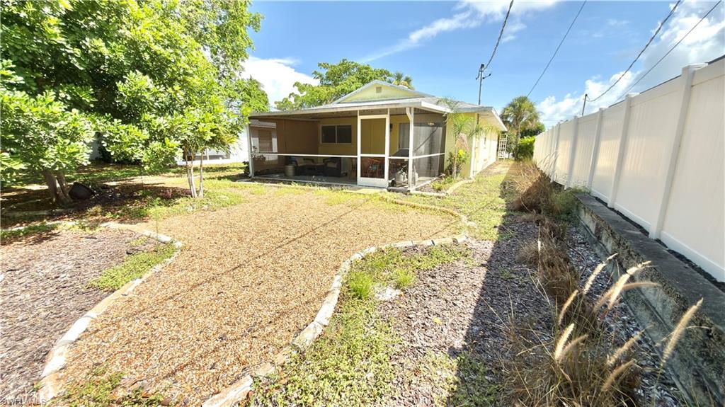 Screened porch, white privacy fencing, gravel path, mature trees, concrete retaining wall