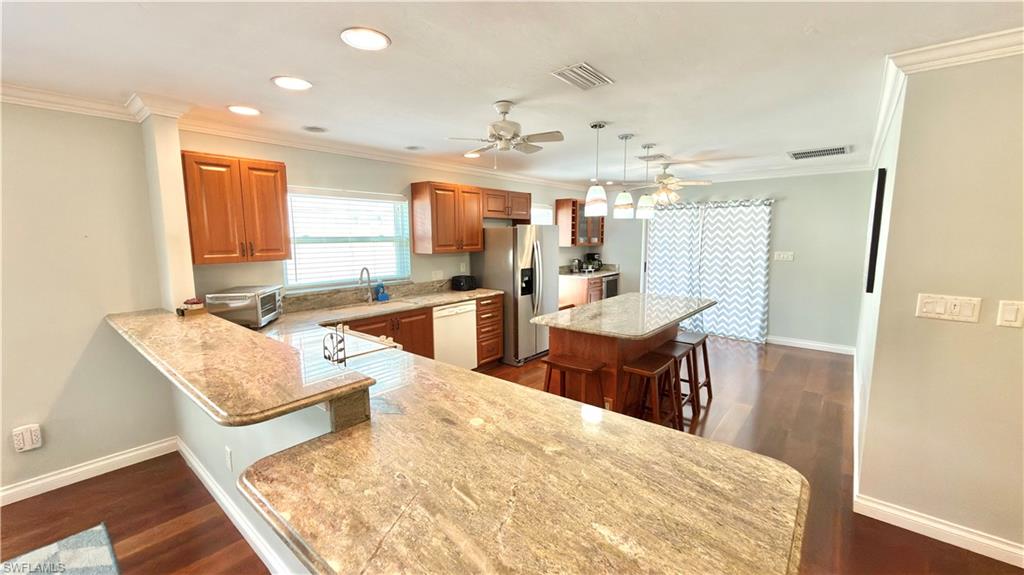 Kitchen featuring a breakfast bar with granite countertops, wood-finish flooring, recessed lighting, and a kitchen island with pendant lighting.