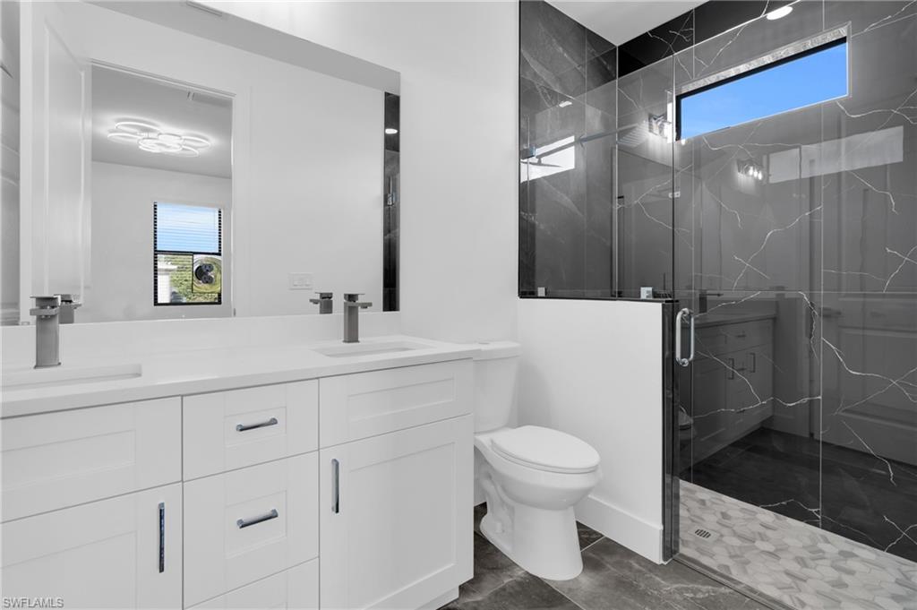 Bathroom with a marble finish shower and double vanity