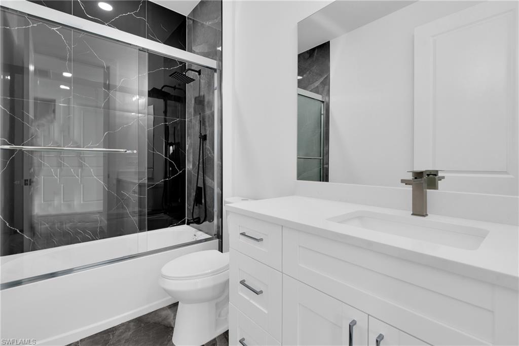 Bathroom with vanity and bath / shower combo with glass door