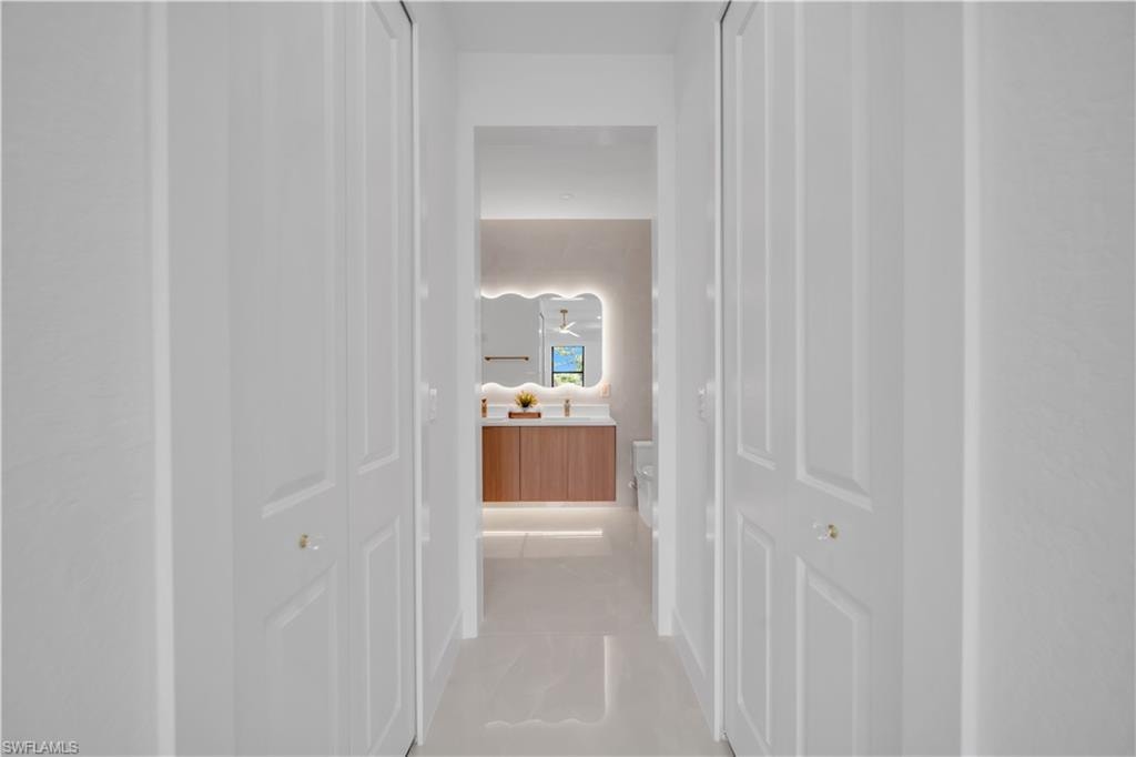 Hallway with white bi-fold doors and tile flooring