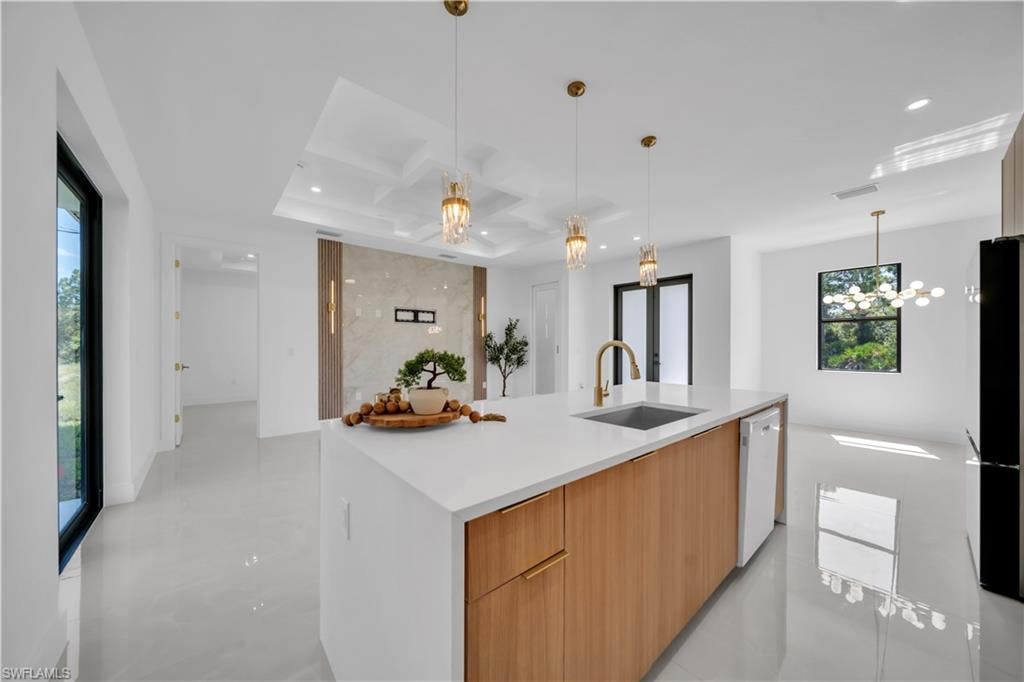 Kitchen island with white countertop, wood-finish cabinetry, and an integrated sink with a gold-tone faucet