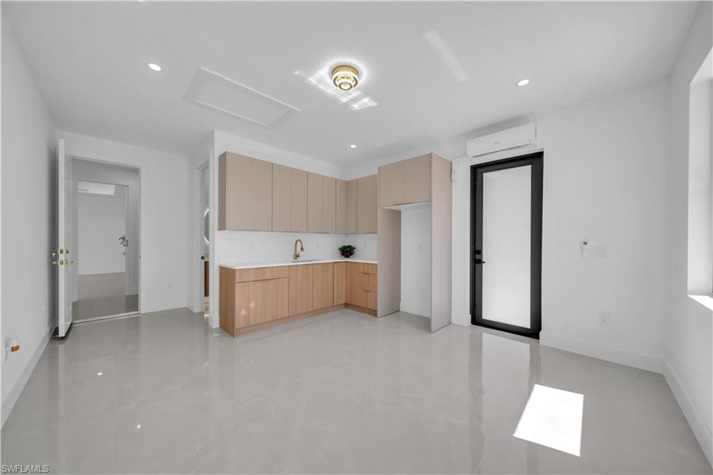 Open concept space featuring light wood-finish cabinetry, white countertops, and a gold-finish faucet
