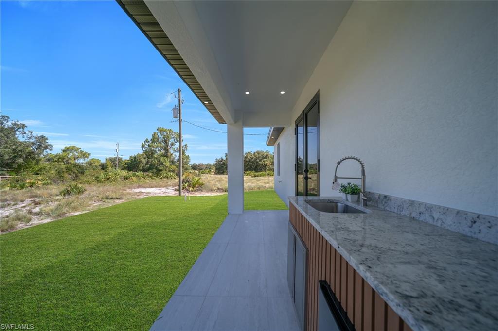 Covered patio featuring an outdoor kitchen with a built-in sink and stone countertop