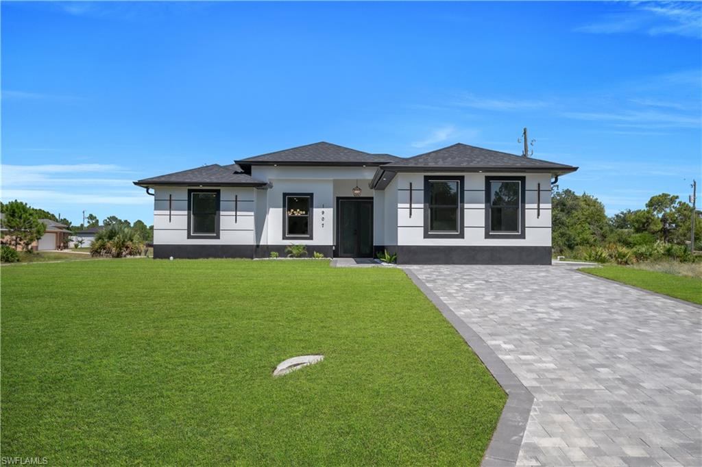 Contemporary exterior with a dark shingle roof, white stucco siding, and a patterned paver driveway