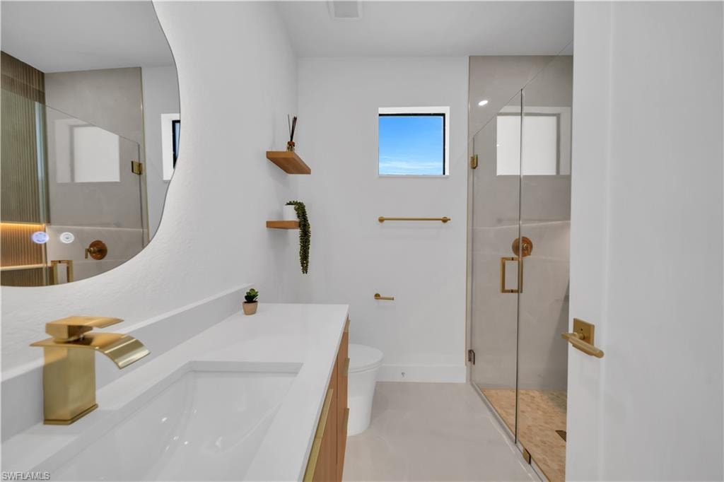 White vanity with an integrated rectangular sink and gold-tone faucet, complemented by a large illuminated wall mirror