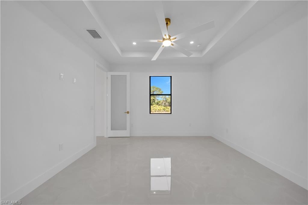 Recessed ceiling with a central fan, large window, and light-toned tile flooring
