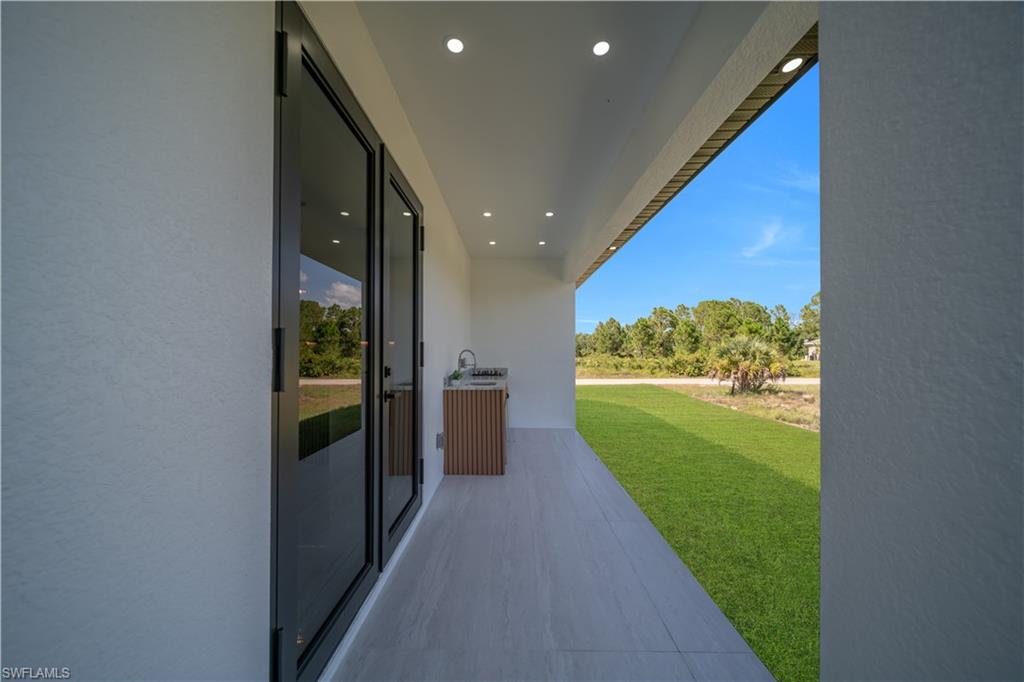 Covered outdoor patio featuring recessed lighting, a built-in outdoor kitchen with a sink, and sliding glass doors