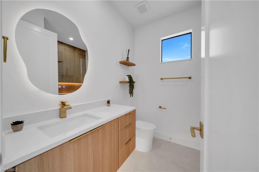 Floating vanity with wood-finish cabinetry, integrated rectangular sink, and gold-tone faucet