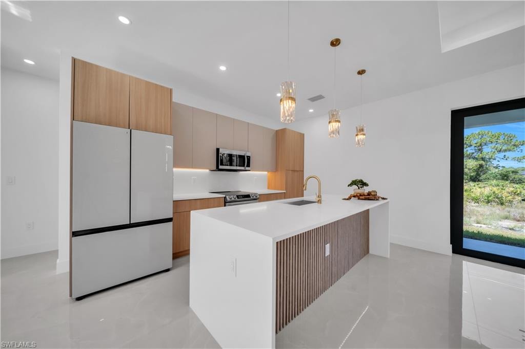 Gourmet kitchen with stainless steel appliances, white countertops, wood-finish cabinetry, and a large center island with integrated storage
