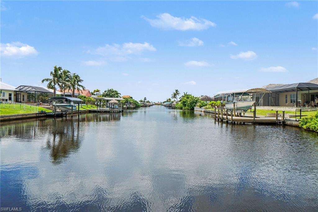 Waterfront property featuring canal access, private docks, screened enclosures, and mature palm trees