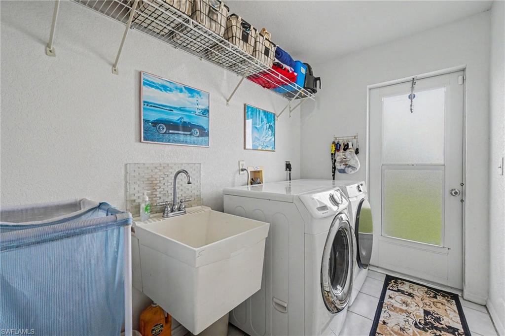 Utility sink with a chrome faucet, wall-mounted wire shelving, and a side-hinged door with frosted glass panels