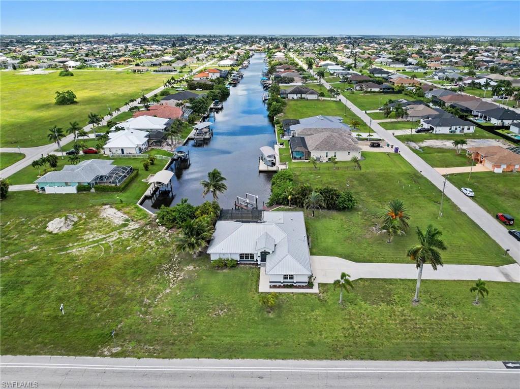 Waterfront property featuring a private boat dock, mature palm trees, and a concrete driveway