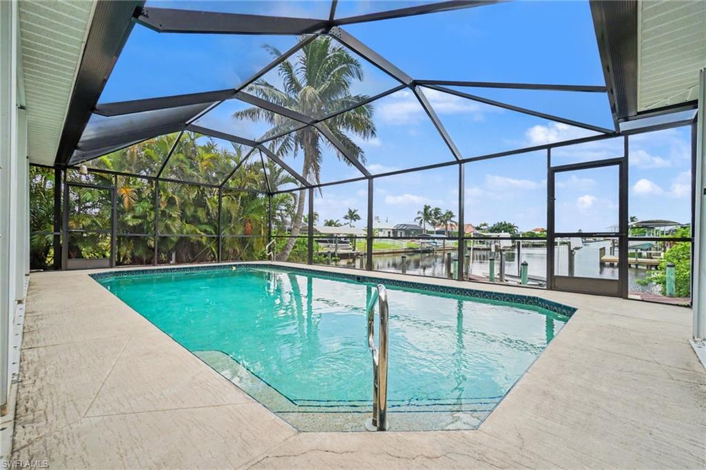 Screened enclosure with an in-ground swimming pool, concrete pool deck, and direct water access