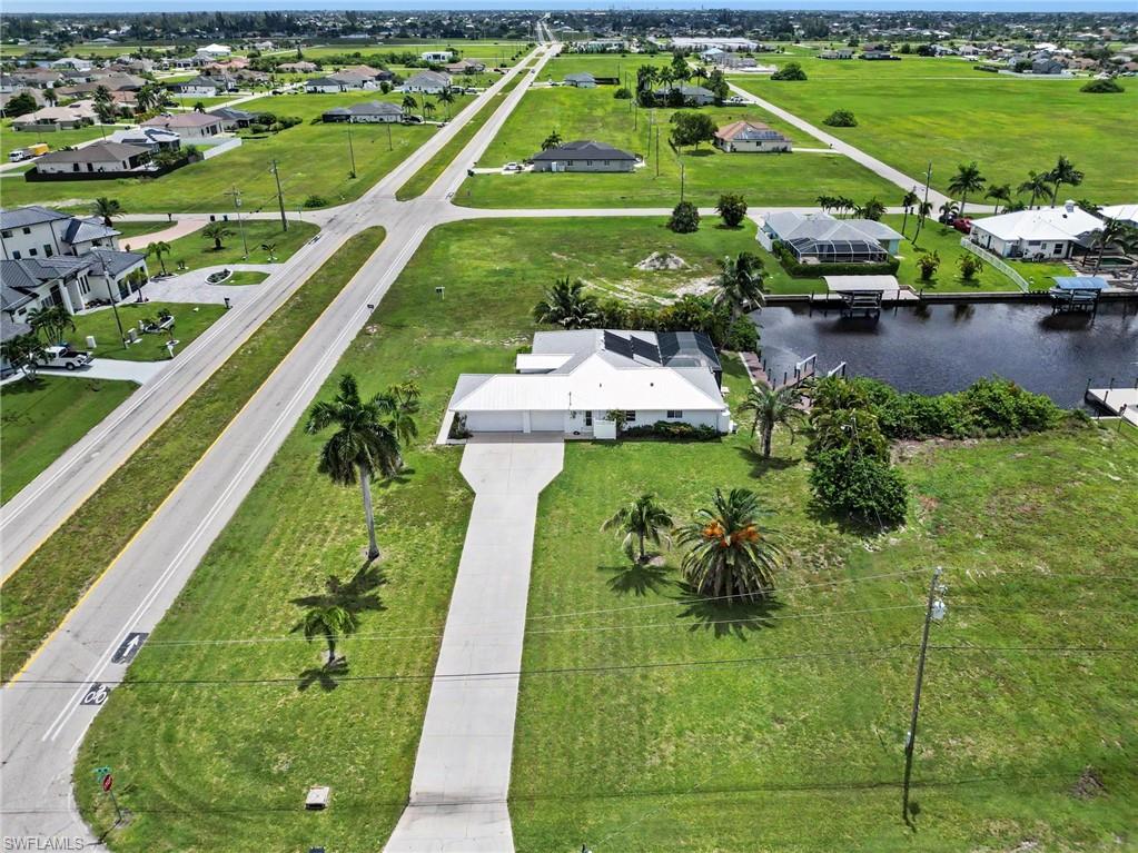 Waterfront property featuring a private boat dock, mature palm trees, and a spacious concrete driveway