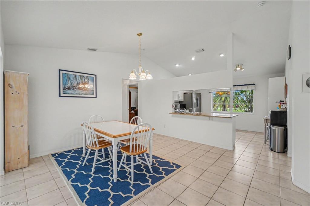 Vaulted ceilings, tile flooring, recessed lighting, and a kitchen pass-through window