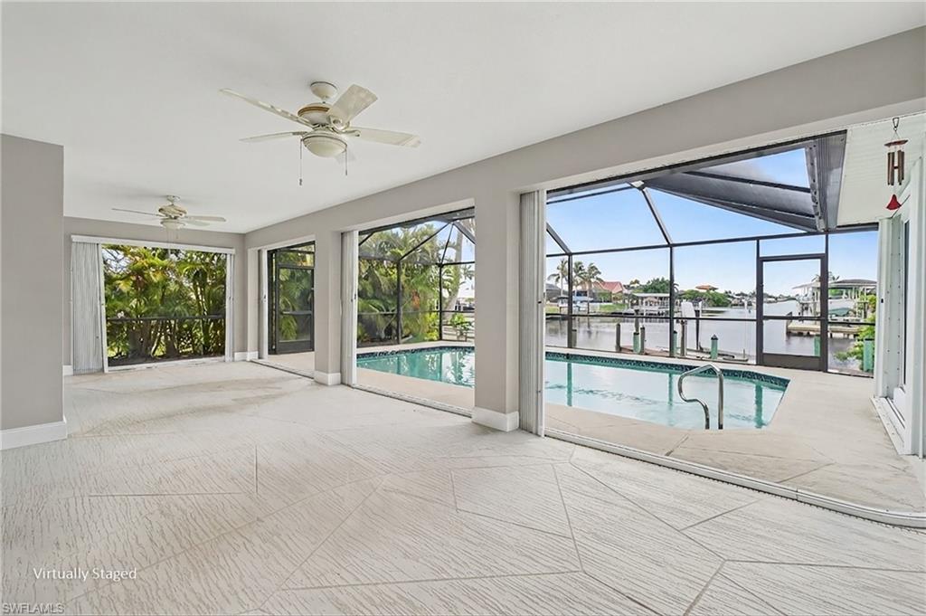 Spacious interior with geometric tile flooring, multiple ceiling fans, and expansive screened pool area