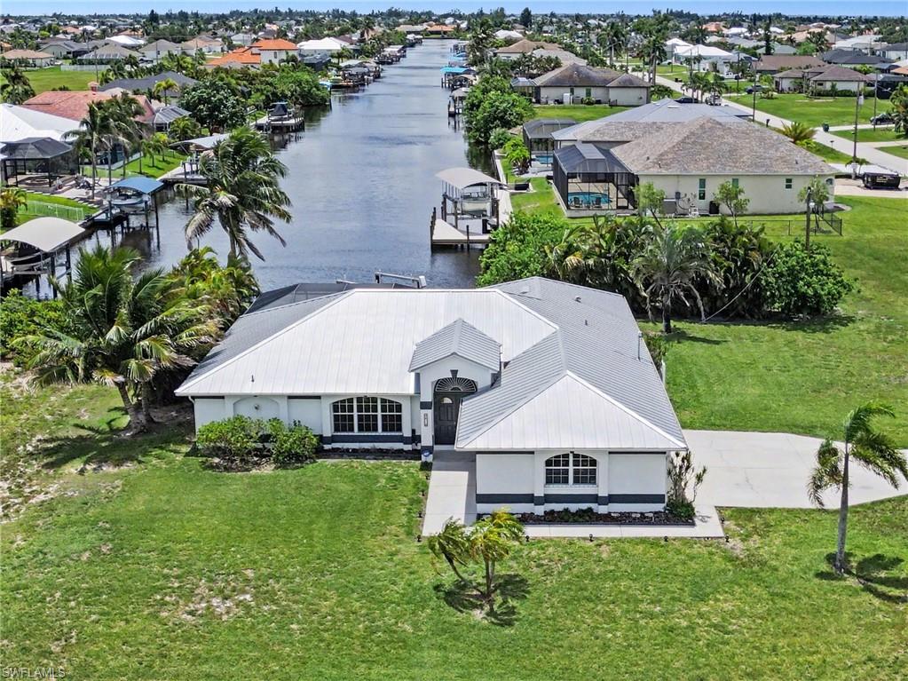 Waterfront property with direct canal access, featuring a private boat dock, a covered boat lift, and an expansive screened-in pool enclosure