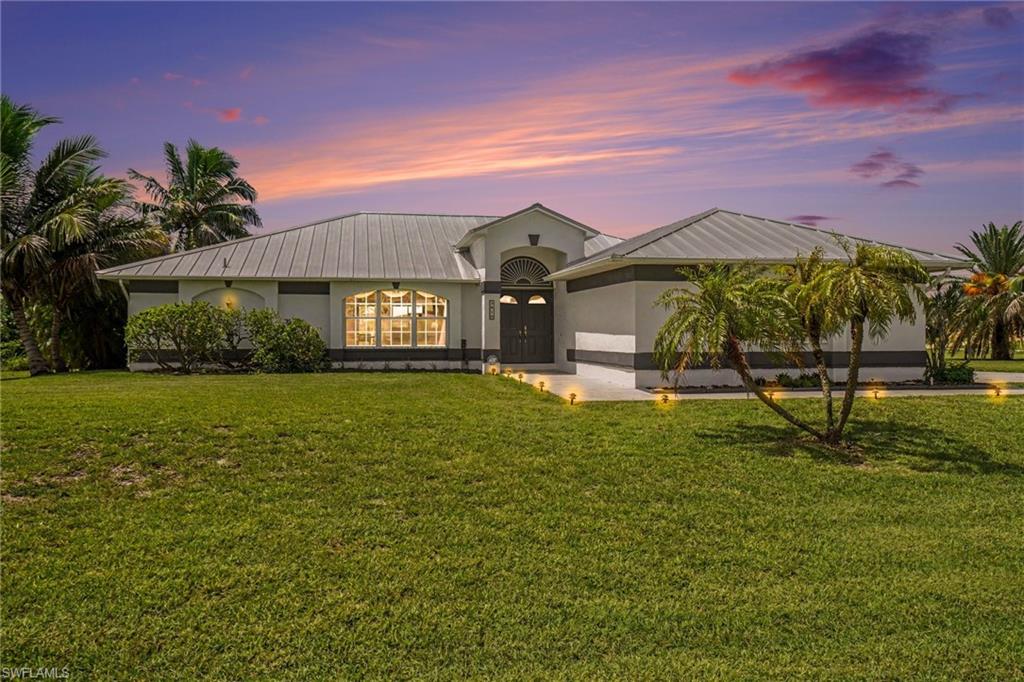 Contemporary exterior with a metal roof, arched transom window, double entry doors, and tropical landscaping