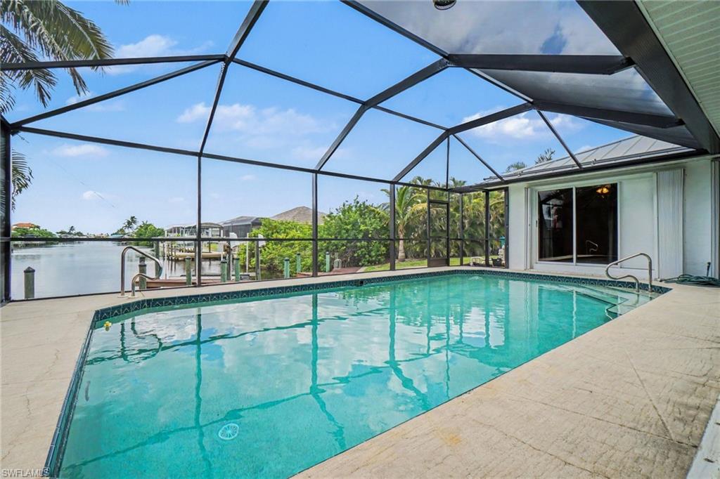 Screened-in pool area featuring a built-in pool, concrete pool deck, and direct water access