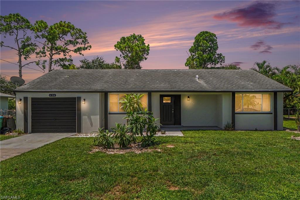 Single-story residence featuring a dark gray shingle roof, a dark gray garage door, and a landscaped front yard with a concrete driveway
