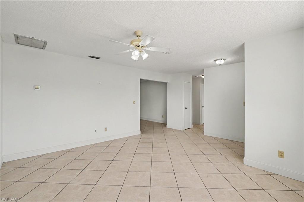 Expansive room featuring neutral-toned tile flooring, a ceiling fan with integrated lighting, and multiple recessed light fixtures