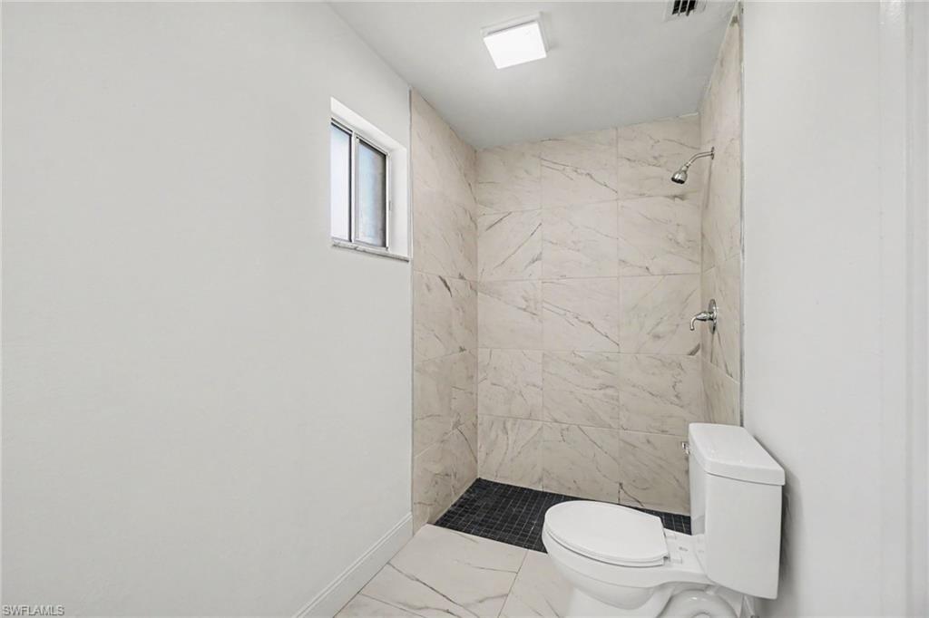 Walk-in shower with large-format tile walls, dark mosaic tile shower floor, and a chrome shower fixture