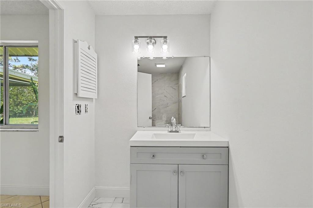Vanity with light gray shaker-style cabinetry, white countertop, and rectangular undermount sink