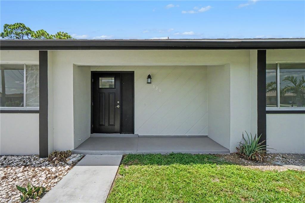 Covered front entry with black paneled door and overhead transom window