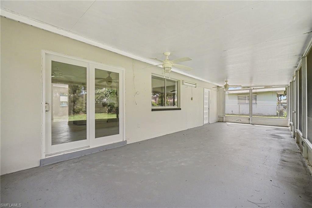 Expansive screened-in porch with a concrete floor, dual ceiling fans, and sliding glass door access to the interior