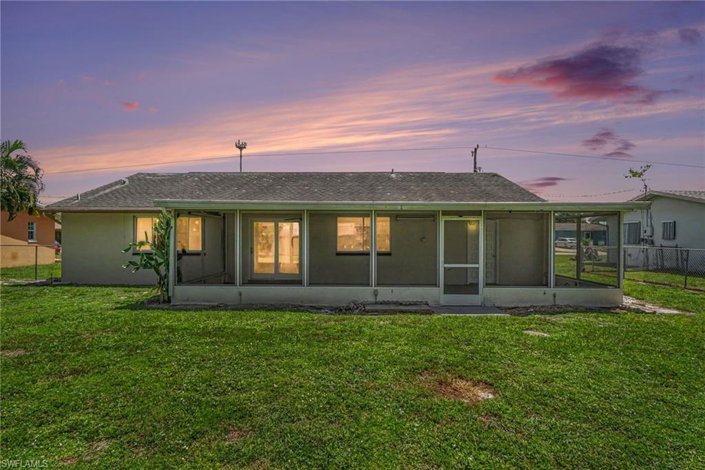 Expansive backyard featuring a screened-in lanai with a concrete slab, multiple windows, and a sliding glass door