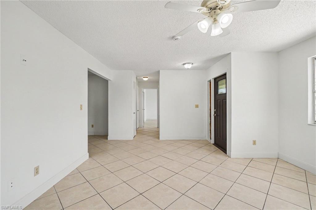 Tiled flooring throughout, ceiling fan with integrated lighting, recessed lighting, and a dark-paneled entry door with a window
