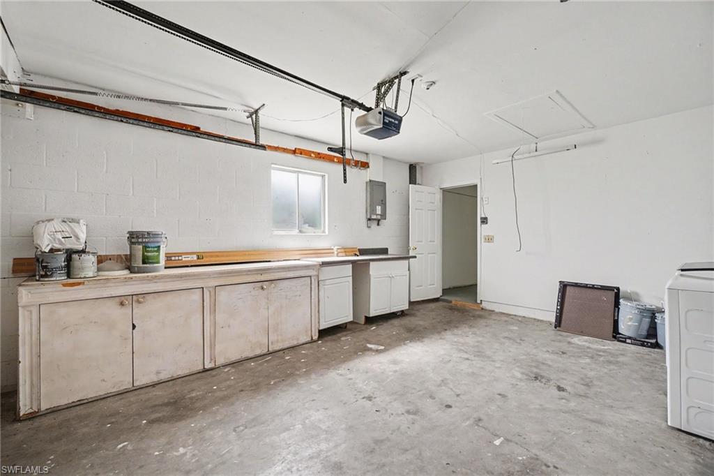 Concrete flooring, built-in cabinetry, window, overhead garage door mechanism, and a white interior door