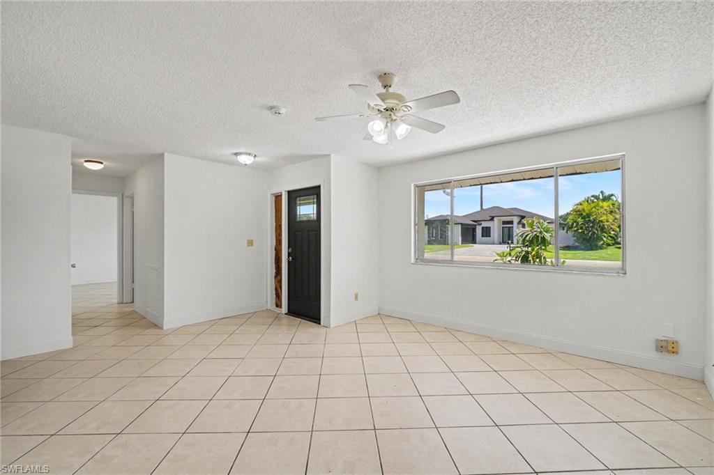 Tile flooring, prominent window, ceiling fan with light fixture, recessed lighting, and a dark entry door