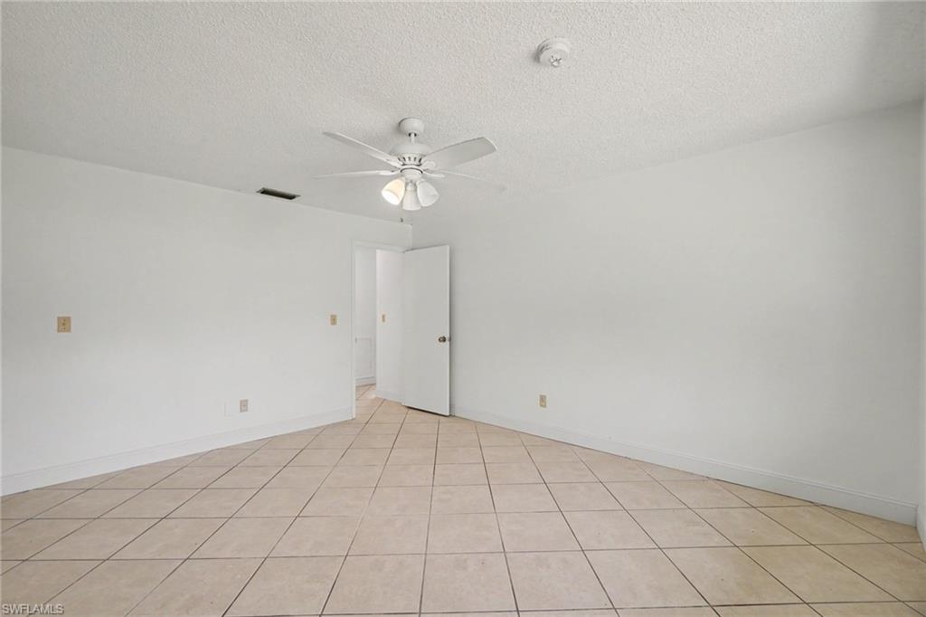 White interior walls, tile flooring, ceiling fan, and white interior doors