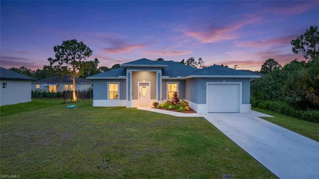Contemporary stucco exterior with a covered entry, established landscaping, and an attached garage