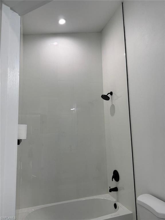 White bathtub with matte black fixtures and a recessed ceiling light