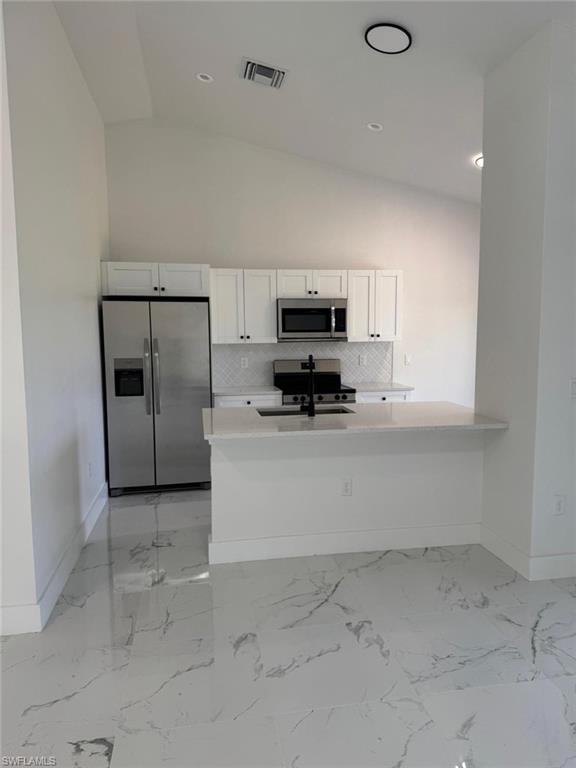 Kitchen featuring stainless steel appliances, white cabinetry, a built-in island with breakfast bar, and tile flooring