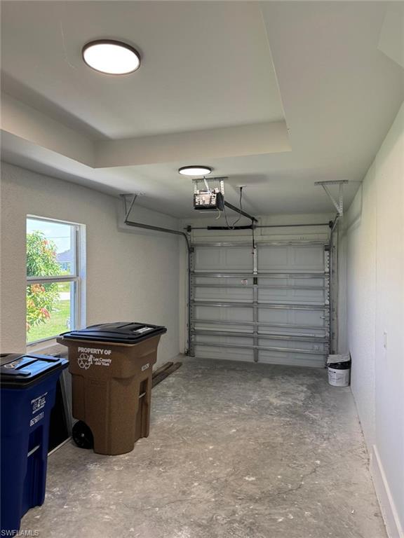 Attached garage featuring a single overhead door, window, and two flush-mount ceiling lights